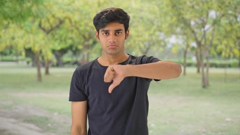 Disappointed-Indian-man-showing-thumbs-down-in-park