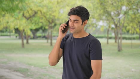 Indian-boy-talking-to-his-girlfriend-on-call-in-park