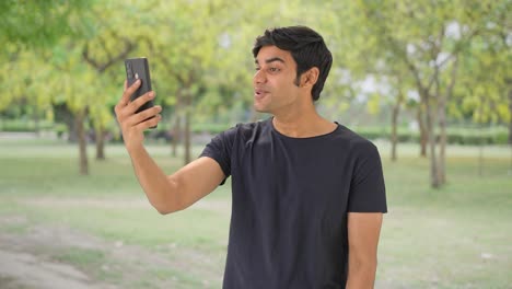 Happy-Indian-boy-talking-on-video-call-at-park
