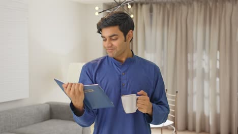 Happy-Indian-man-drinking-tea-and-reading-book