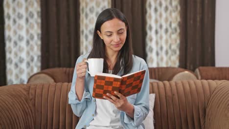 Happy-Indian-woman-drinking-tea-and-reading-a-book
