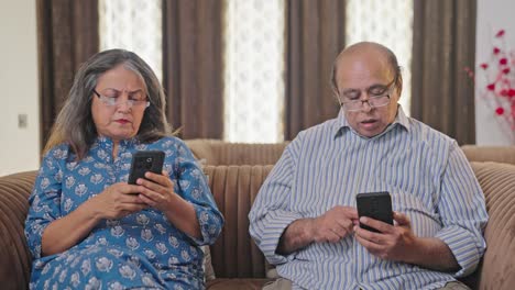 Una-Pareja-De-Ancianos-Indios-Ocupados-Con-Su-Teléfono-Y-Sin-Hablarse