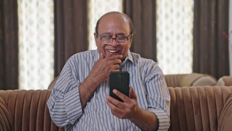 Anciano-Indio-Riéndose-Después-De-Ver-Algo-Gracioso-En-Un-Teléfono-Móvil