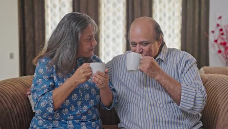 Happy-Indian-old-couple-enjoying-morning-tea-and-smiling