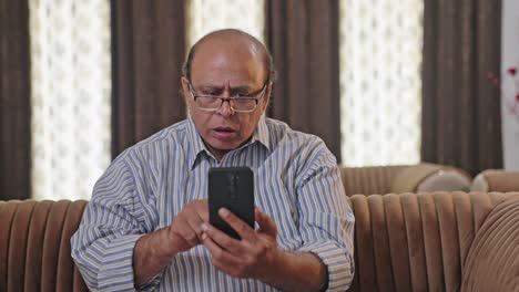 Indischer-Alter-Mann-Sieht-Eine-Schockierende-Nachricht,-Während-Er-Durch-Das-Telefon-Scrollt