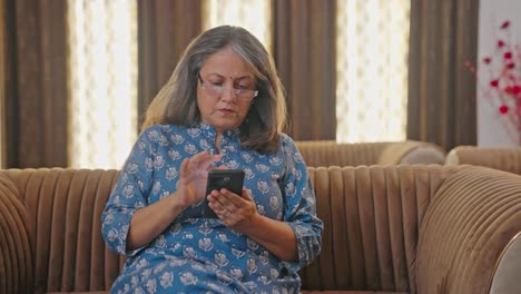 Ältere-Indische-Frau,-Die-Durch-Ihr-Mobiltelefon-Scrollt