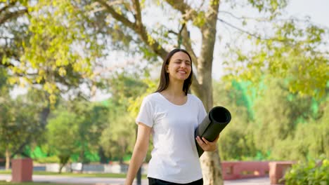Mujer-India-Caminando-Con-Estera-De-Yoga-En-Un-Parque-Por-La-Mañana