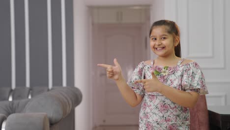 Indian-kid-girl-pointing-on-the-left-side-for-copyspace