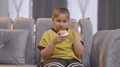 Confused-Indian-kid-girl-trying-to-solve-a-Rubik's-cube