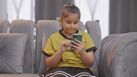 Bored-Indian-kid-girl-scrolling-through-mobile-phone-aimlessly