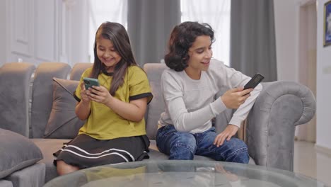 Glückliche-Indische-Kinder,-Die-Mit-Ihren-Telefonen-Beschäftigt-Sind-Und-Nicht-Miteinander-Reden