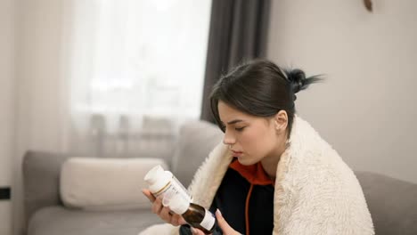 Sick-woman-in-blanket-reading-labels-and-choosing-between-two-bottles