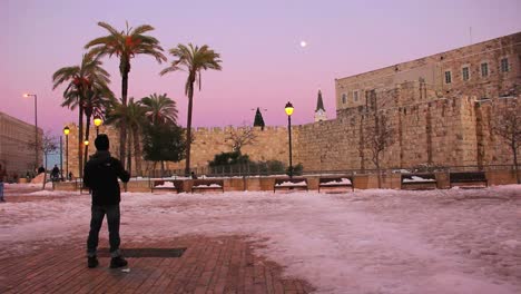 Un-Hombre-Se-Encuentra-En-Una-Plaza-De-Jerusalén-Al-Anochecer-Tras-Una-Rara-Caída-De-Nieve