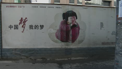 Chinese-factory-workers-walk-home-through-an-alleyway-and-past-a-large-billboard