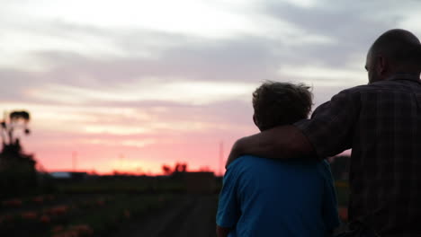 A-father-and-son-sit-in-a-farm-field-at-sunset-3