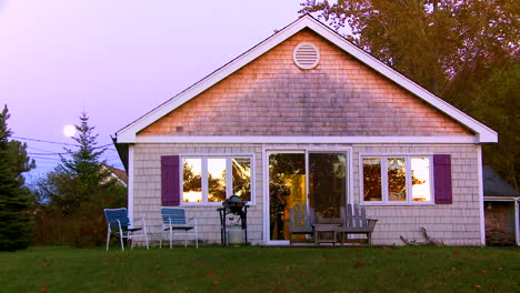 Nice-dusk-establishing-shot-of-a-summer-cottage-in-New-England-or-Maine-with-moon-rising