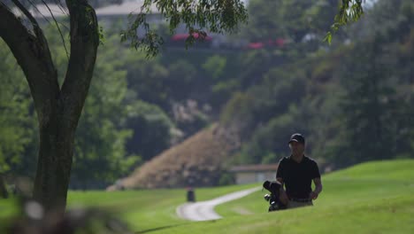 Ein-Golfspieler-Trägt-Seine-Schläger,-Während-Er-Auf-Einem-Golfplatz-Einen-Hügel-Hinaufgeht