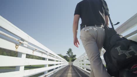 A-golfer-walks-up-a-walkway-away-from-the-camera-as-the-camera-pulls-back