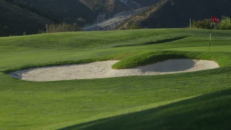 Wide-view-of-a-sand-trap-at-a-golf-course-with-mountains-in-the-background
