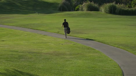 A-golfer-walks-along-a-path-on-a-golf-course