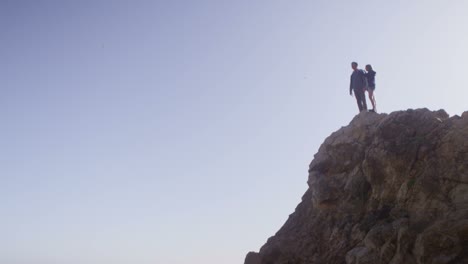 Wide-view-of-a-couple-standing-atop-a-sea-cliff