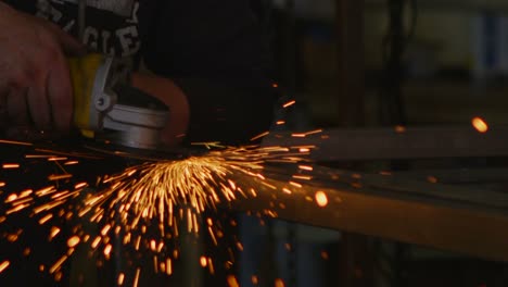 Sparks-fly-as-a-worker-edges-with-a-tool-in-a-workshop