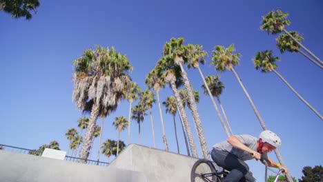 Low-angle-view-of-a-BMX-bike-rider-executing-a-jump-at-a-skatepark