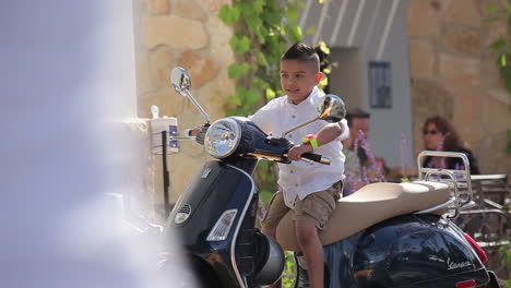 A-young-boy-is-delighted-to-sit-on-a-Vespa-motorscooter