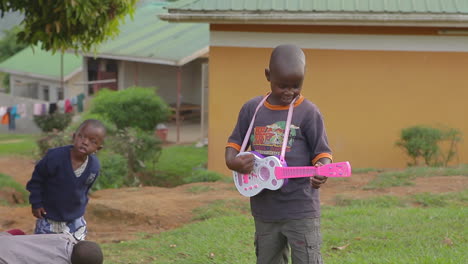Ein-Afrikanischer-Junge-Spielt-Eine-Rosa-Gitarre-In-Uganda