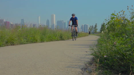 A-man-rides-a-montaña-bike-along-a-public-park-trail-with-the-city-of-Chicago-skyline-background