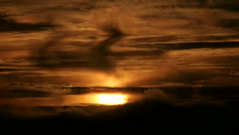 Clouds-move-quickly-over-the-orange-sun-in-a-darkening-sky