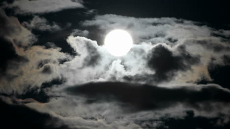 A-bright-full-moon-rises-as-clouds-move-quickly-in-a-night-sky