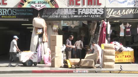 Los-Vendedores-De-La-Tienda-Descargan-El-Stock-En-Frente-De-Su-Tienda-En-El-Centro-De-Los-Ángeles,-California