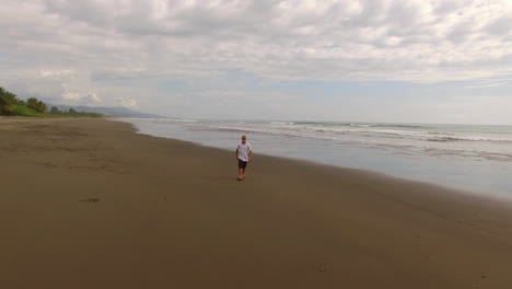 Ein-Mann-Springt-Auf,-Um-Sich-Eine-Drohne-Zu-Schnappen,-Die-über-Einen-Strand-Von-Costa-Rica-Fliegt