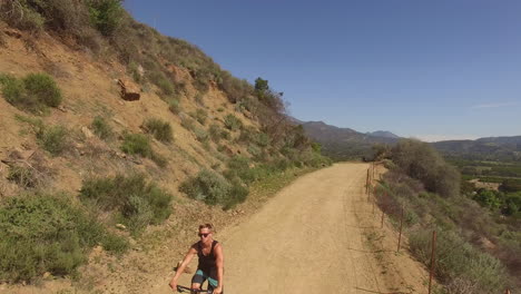 Ein-Mountainbiker-Lässt-Beim-Radfahren-Eine-Drohne-Los-Und-Bewegt-Sich-Dann-Mit-Hoher-Geschwindigkeit-Durch-Eine-Landschaft