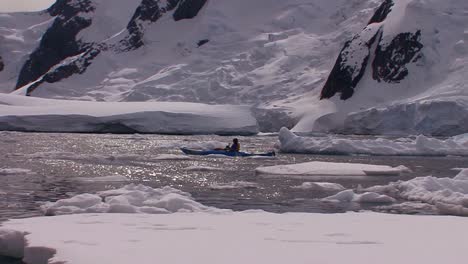 Un-Hombre-Rema-En-Kayak-Por-La-Región-ártica-O-Antártica-Cerca-De-Vastos-Campos-De-Hielo-Y-Glaciares