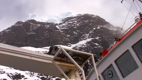 Low-angle-of-an-oceanic-research-vessel-passing-below-high-cliffs-in-Antarctica