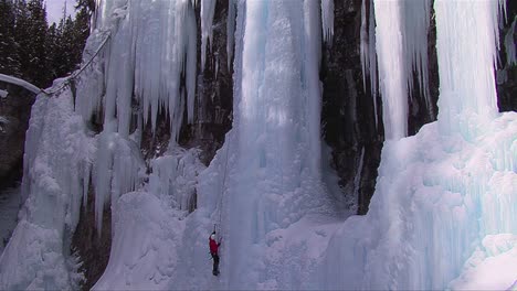Wide-shot-of-a-man-climbing-up-a-frozen-waterfall