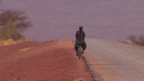 Ein-Mann-Fährt-Mit-Dem-Fahrrad-Auf-Einer-Abgelegenen-Straße-Durch-Die-Sahara-Across