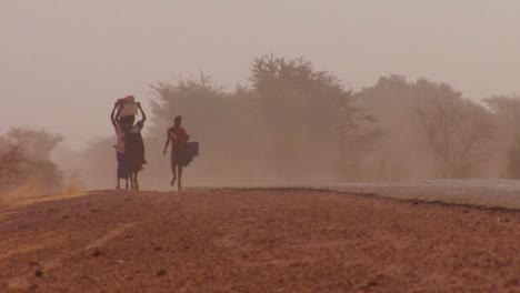 Las-Mujeres-Caminan-Cargando-Mercancías-Sobre-Sus-Cabezas-A-Través-Del-Desierto-Del-Sahara-En-Malí-1