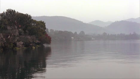 Ein-Ruhiger-See-In-Ländlicher-Umgebung-Mit-Strohgedeckten-Häusern,-Die-Am-Ufer-Sichtbar-Sind