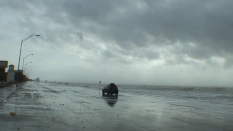 Riesige-Wellen-Schlagen-Während-Eines-Massiven-Hurrikans-Oder-Sturms-Auf-Eine-Ufermauer-In-Galveston,-Texas,-Wenn-Ein-Auto-Vorbeifährt