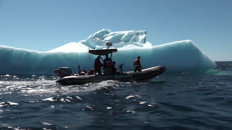 Men-in-a-zodiac-boat-pass-a-massive-iceberg-in-the-Arctic