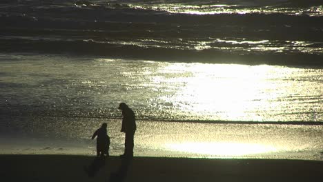Ein-Mann-Und-Zwei-Kinder-Erkunden-Den-Strand-Bei-Ebbe-Während-Der-Goldenen-Stunde
