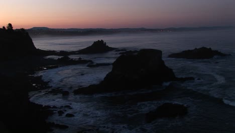 A-Broad-Band-Of-Pink-And-Orange-Sky-Brightens-This-Footage-Of-A-Gray-Rocky-Coastline