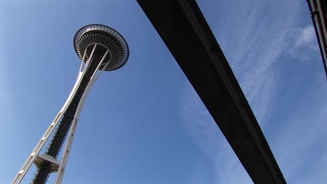 Eine-Schräge-Ansicht-Der-Space-Needle-Von-Seattle-Und-Der-Unterseite-Der-Monorail,-Die-In-Der-Nähe-Verläuft