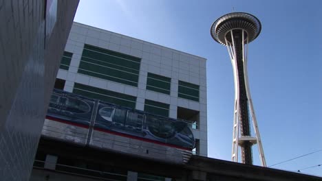 A-Lowangle-View-Of-The-Monorail-Passing-The-Space-Needle-And-Other-Downtown-Seattle-Buildings