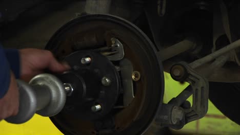 A-Mechanic-Tightens-Bolts-On-A-Wheel-Being-Fastened-To-An-Axle