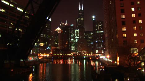 Eine-Wunderschöne-Nachtaufnahme-Von-Chicagos-Downtown-Gebäuden-Von-Der-Anderen-Seite-Des-Wassers-Aus