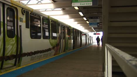 Passengers-Exit-A-Colorful-Commuter-Train-Before-It-Departs-As-Another-Train-Arrives-At-The-Station